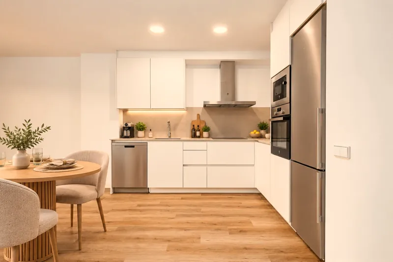 Cocina en L con muebles blancos, horno y microondas integrados
